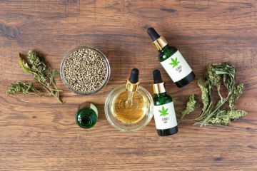 Green bottles of medical CBD oil with cannabis seeds
