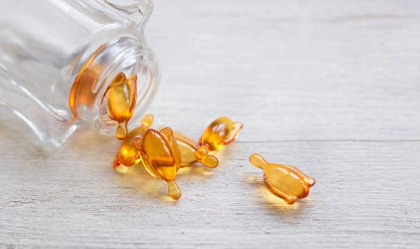 Skin and hair vitamin serum orange capsules on white table